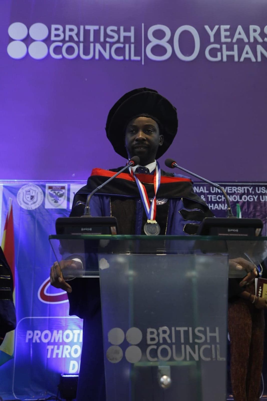Dr Divine Oshideko speaking in academic regalia at a leadership event
