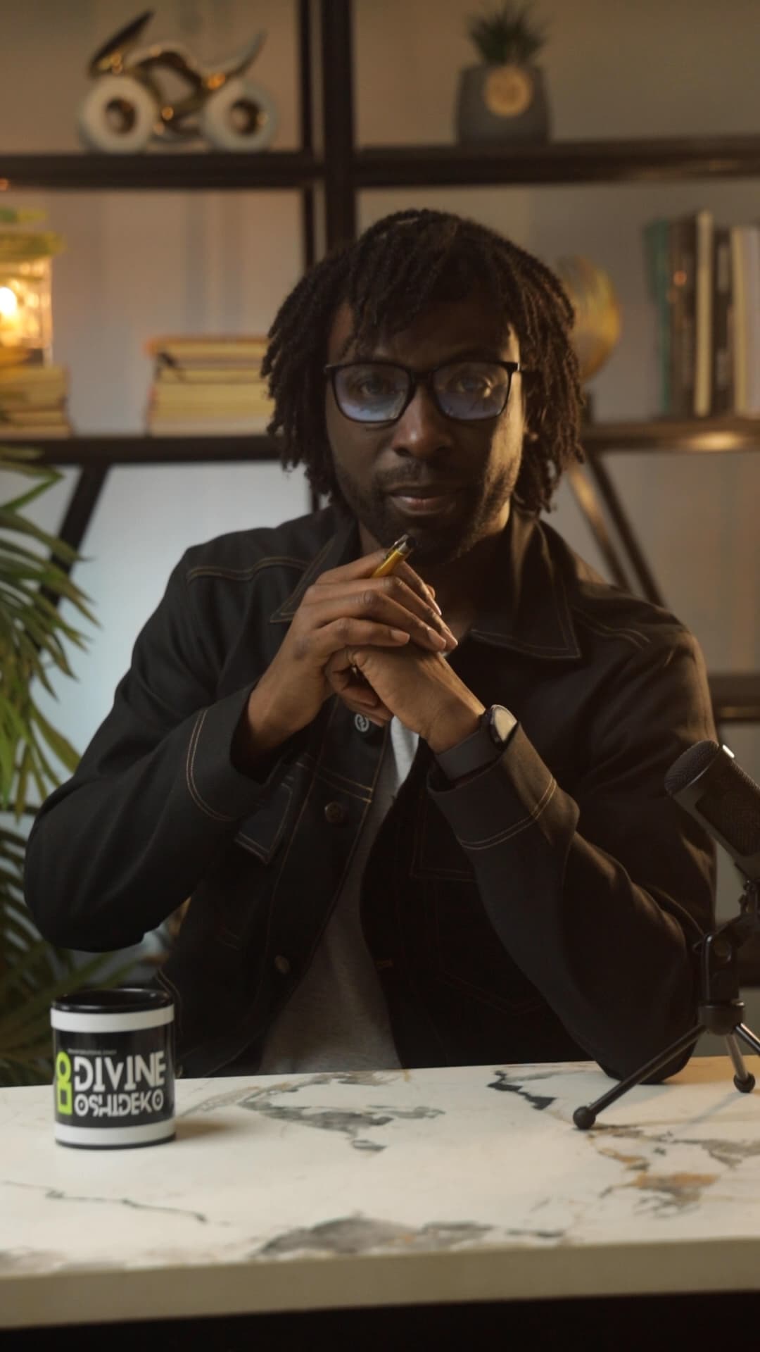 Divine Oshideko seated in the studio beside a microphone